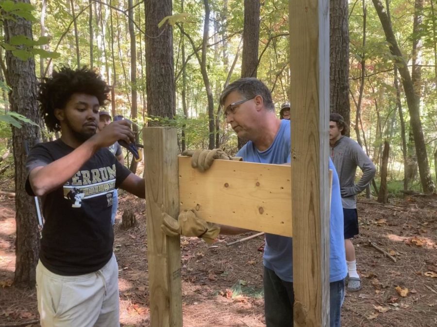 At left, Hailu Grimes-Whited, senior, and Dan Caston, Professor of Recreation and Leadership, install one of 26 posts needed for the Natures Writers Trail.