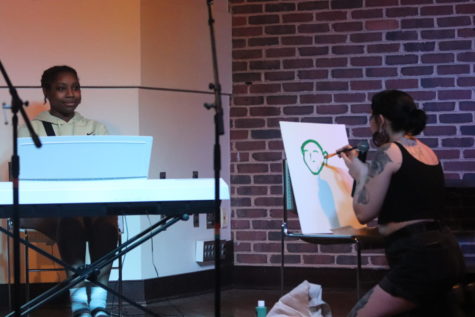 Scout Lynch, sophomore, performs a song and paints a picture of Makaila Veney, junior, at a previous coffee house.