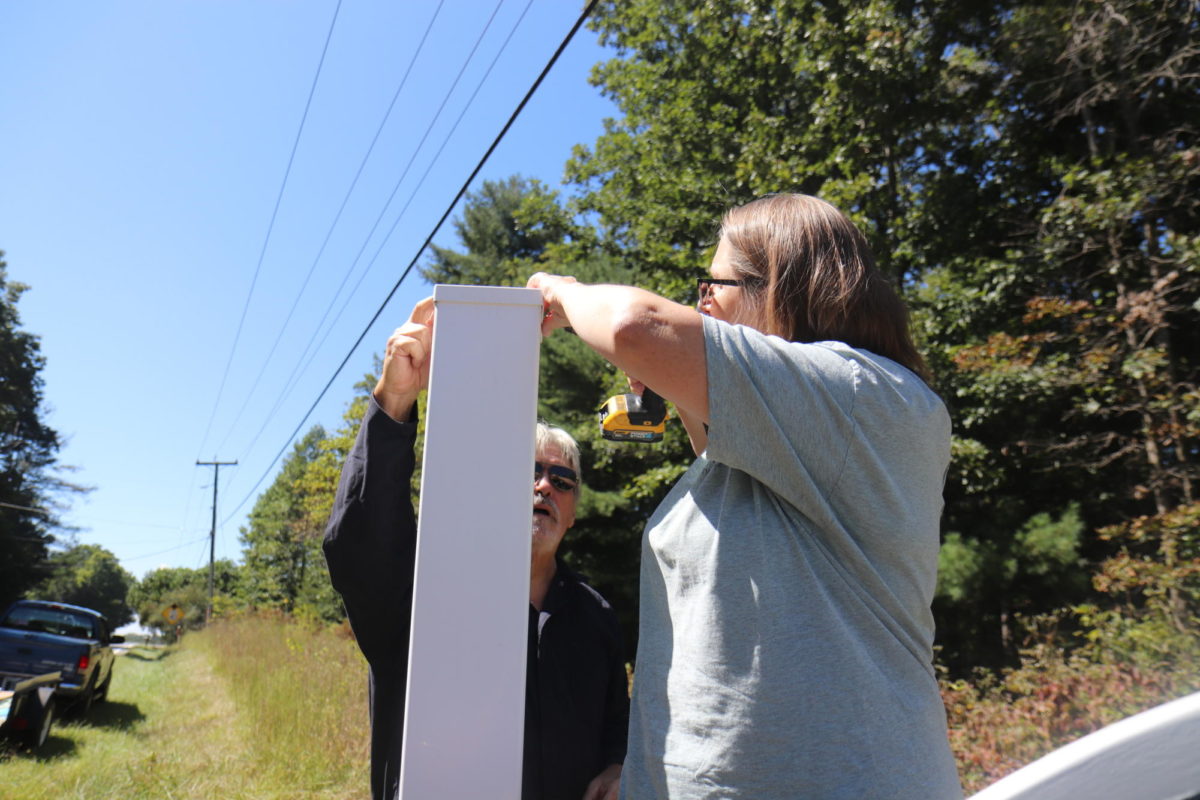 Don Vineyard, left, helps steady the post sleeve as Mary Turner drills holes.