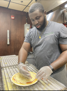 Joseph Bissue makes a pizza during his shift at Panther Pizza on campus.