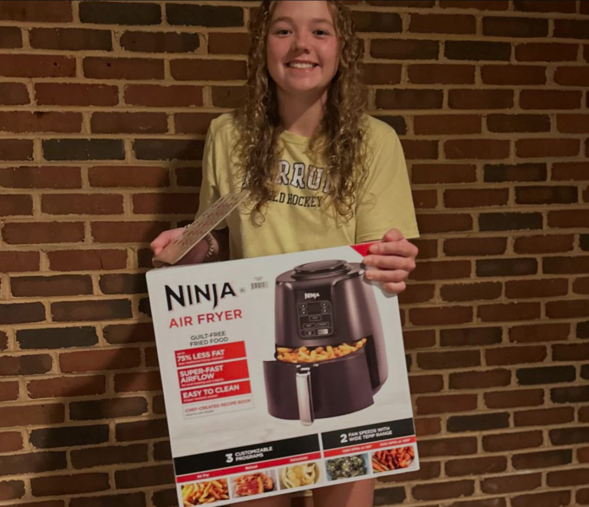 Erin Harden, junior, stands with her air fryer after winning in BINGO.