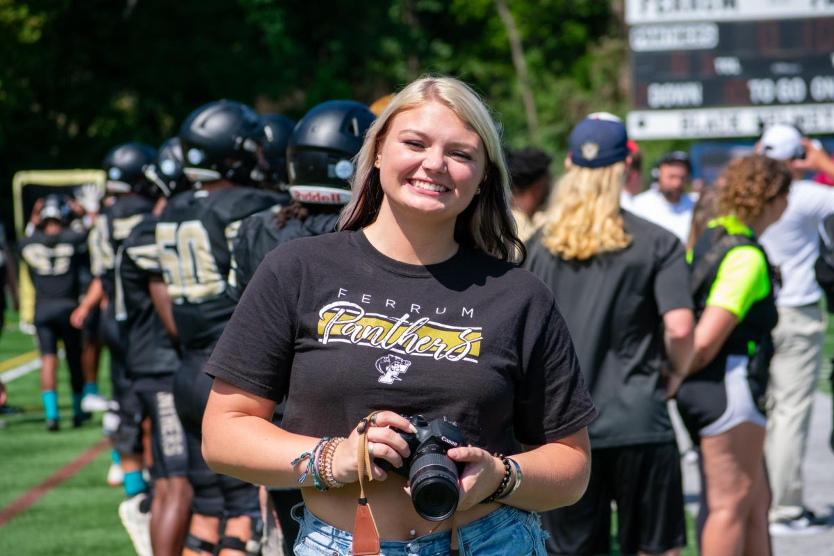 Senior Taylor Huck smiles for a photo as she reviews those of her own at a Panther's football game.