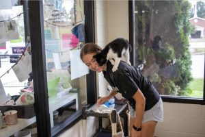 Senior Jamie Adams plays with a cat in Women's Soccer day of service.