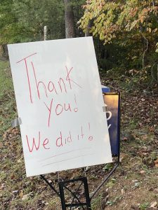 A hand-written sign hangs over the Ferrum Forward sign announcing that Friends of Ferrum Park raised enough money to purchase the land for the park.