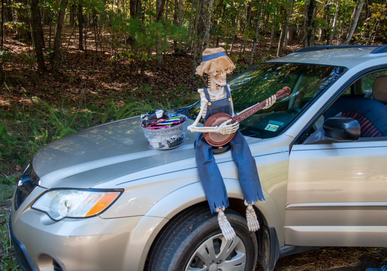 A skeleton sits upon a car with candy, forewarning trail-goers to beware. 