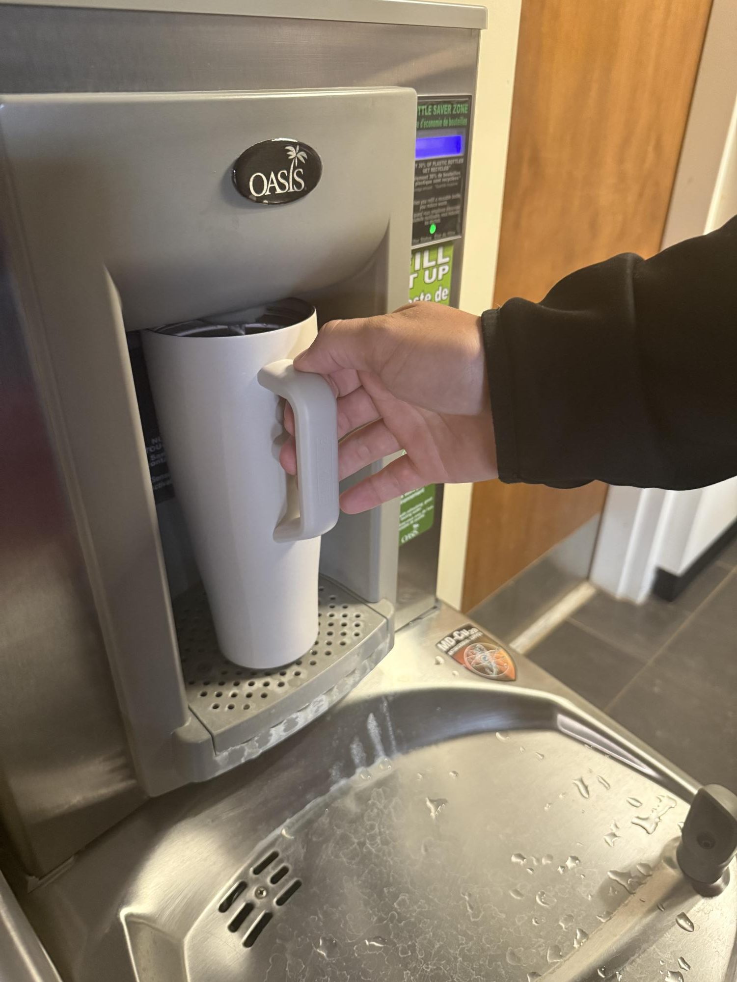 A student uses the fill station in Stanley Library to refill a thermos. 