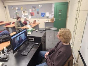 Senior Stone Gibbs speaks to NPR team member Lulu Miller over zoom while other students prepare their questions. 