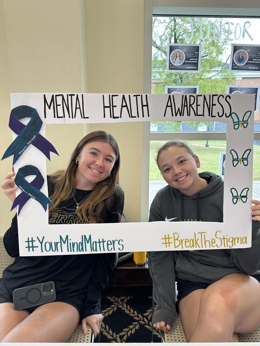 Senior Erin Harden and Junior Bre Herlihy hold the mental health awareness sign. 