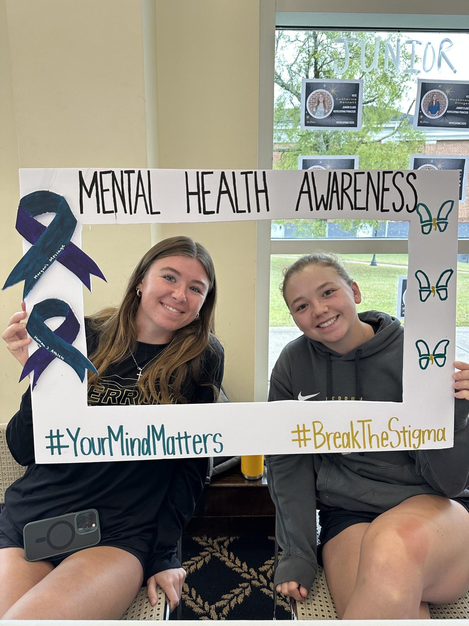 Senior Erin Harden and Junior Bre Herlihy hold the mental health awareness sign. 