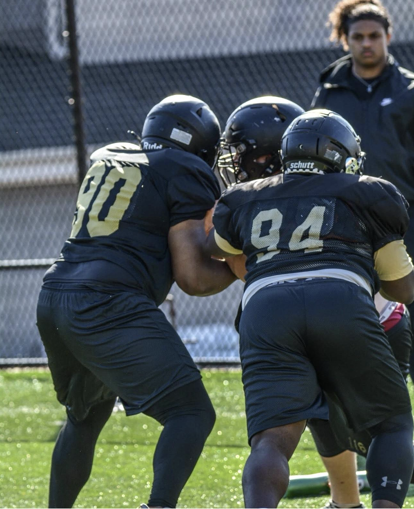 Sophomore Desean Lucas, left, and Myles Chambers, right, work together to prevent a player from rushing through the  gap.