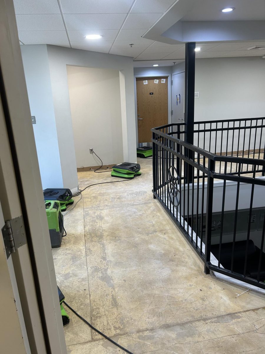 Industrial fans blow to help dry Moore Hall and reduce mold growth. All the carpeting has been stripped from the floors.
