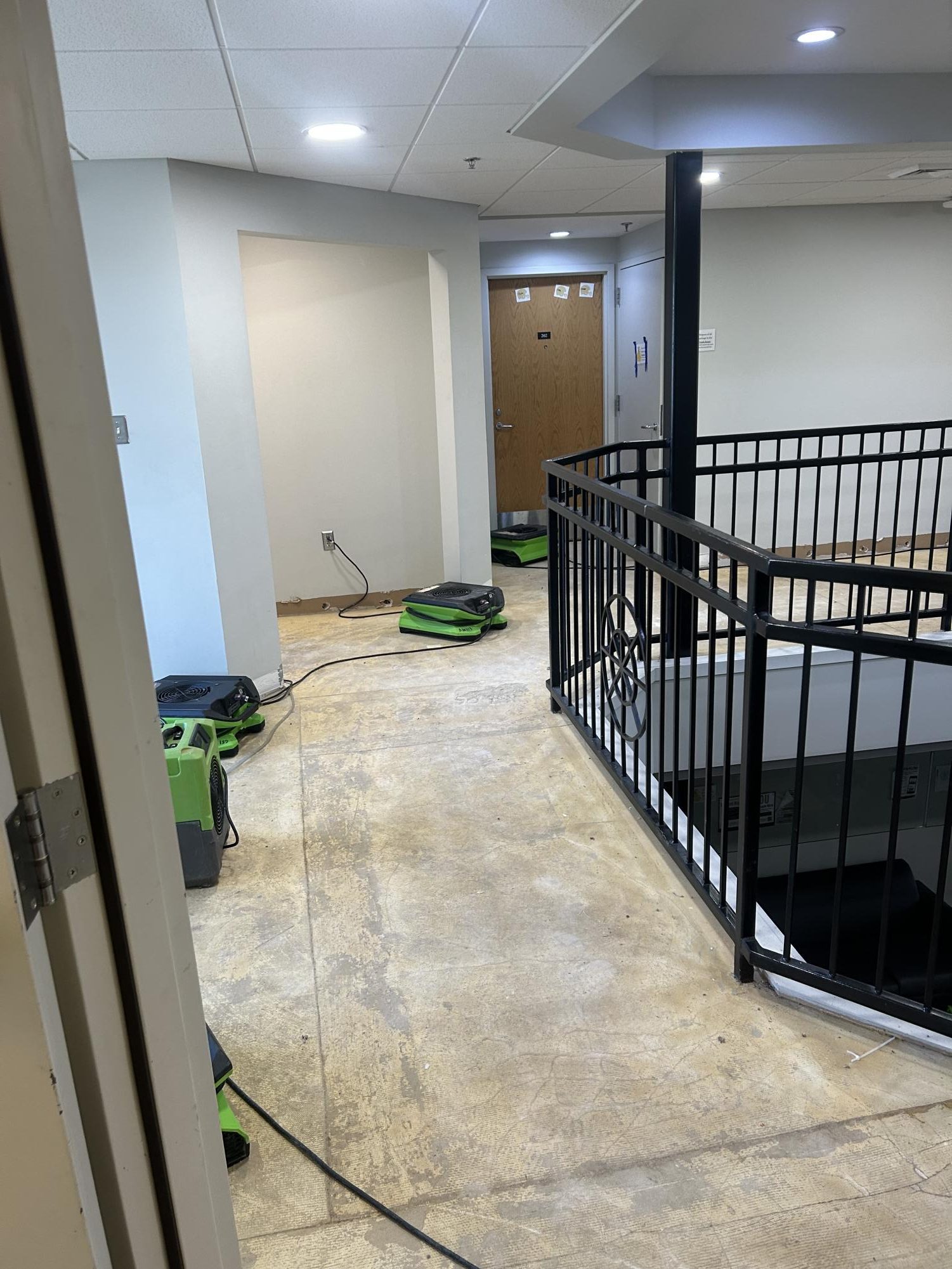Industrial fans blow to help dry Moore Hall and reduce mold growth. All the carpeting has been stripped from the floors.
