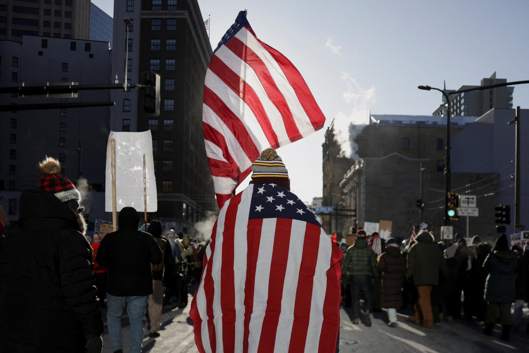 A demonstrator carries flags on the day of a general strike to protest U.S. President Donald Trump's deployment of thousands of immigration enforcement officers on the streets of Minneapolis, Minnesota, U.S., January 23, 2026.  REUTERS/Evelyn Hockstein